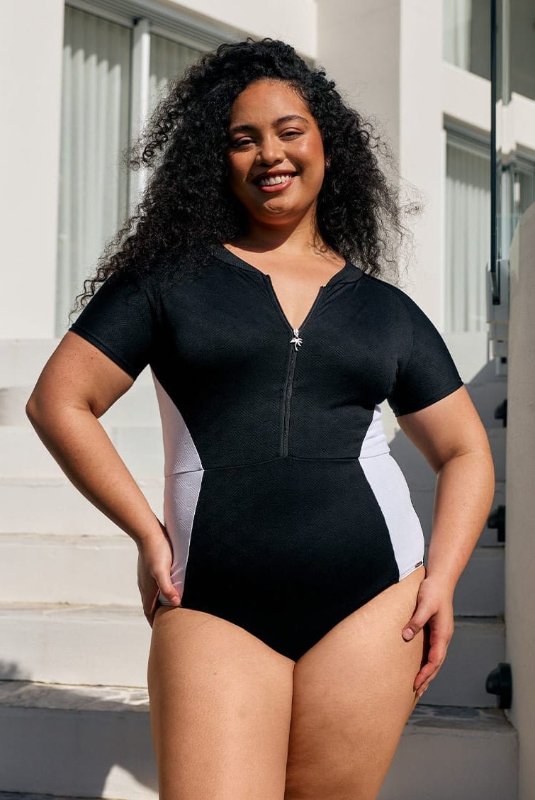 Model by pool wearing a zip front one piece with black and white panel detail