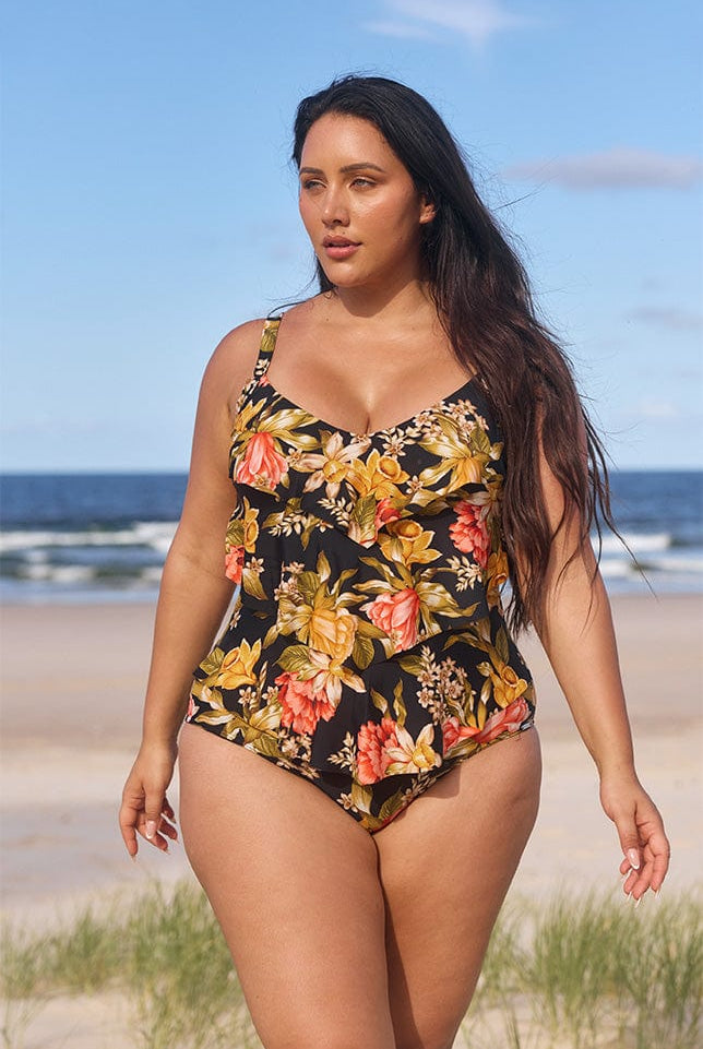 model wearing black and gold floral 3 tier one piece on beach
