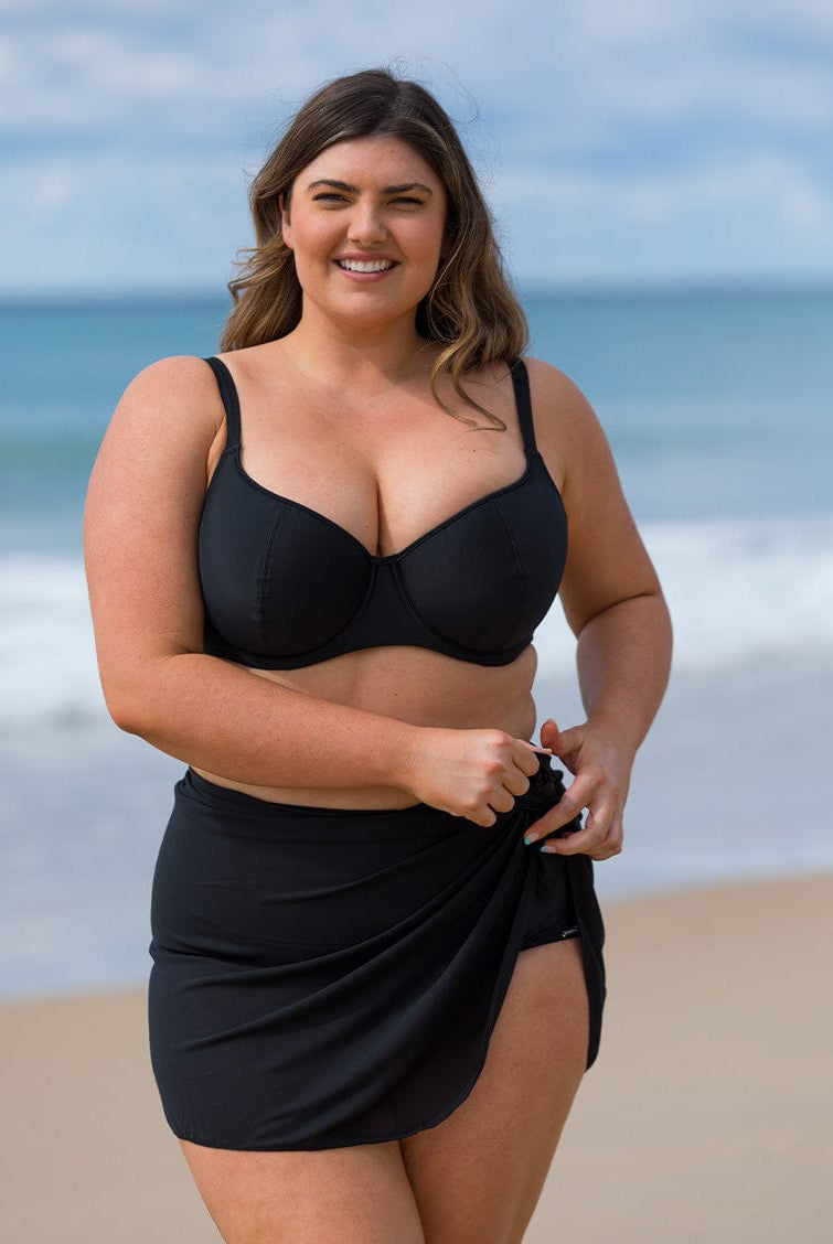 model wearing black mesh tie skirt with black bikini top on beach