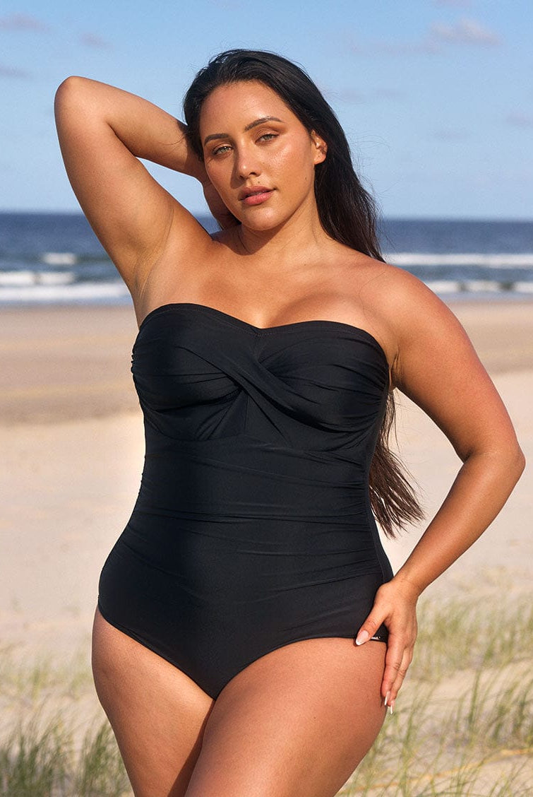 model wearing black strapless swimsuit at beach