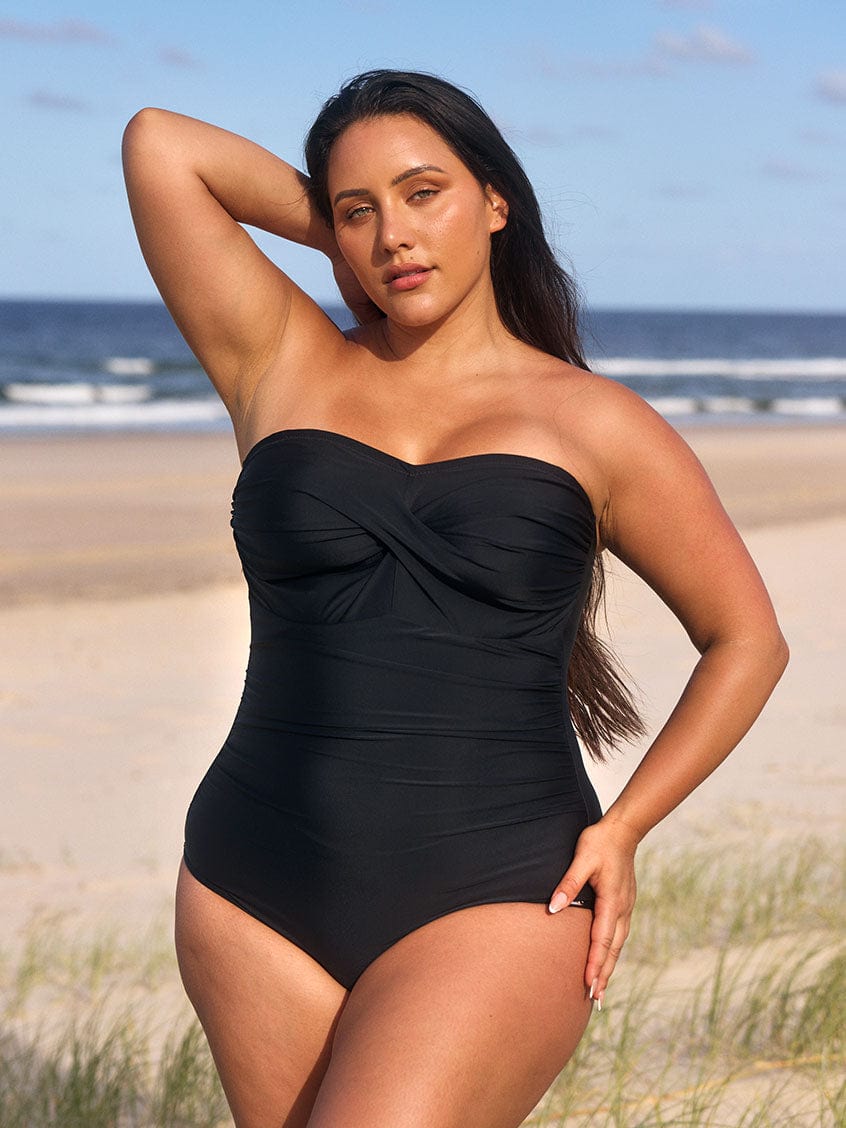 model wearing black strapless swimsuit at beach