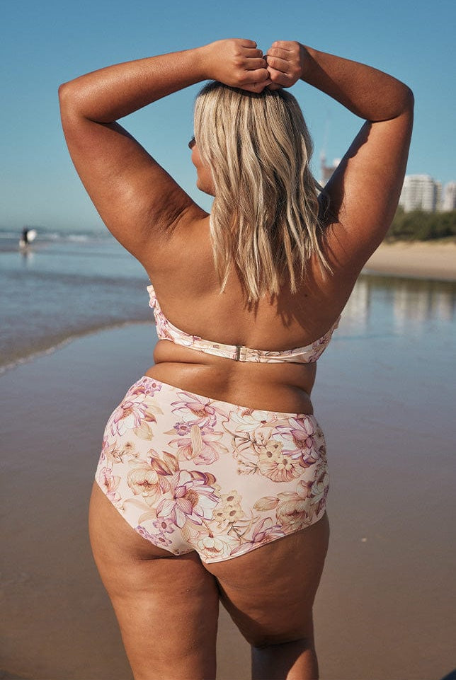 Blonde model showing back of light pink floral bikini on beach
