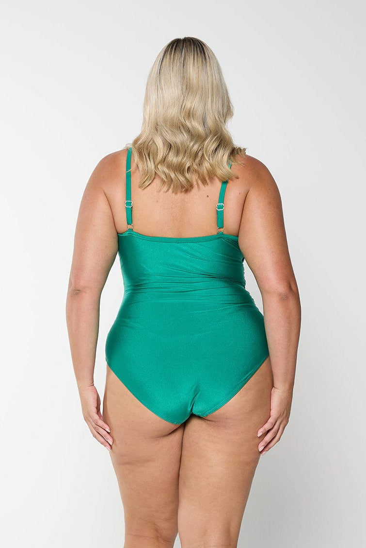 Back of blonde model in studio wearing plus size one piece in metallic green colour with criss cross detail