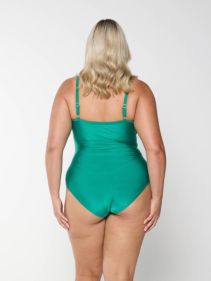 Back of blonde model in studio wearing plus size one piece in metallic green colour with criss cross detail