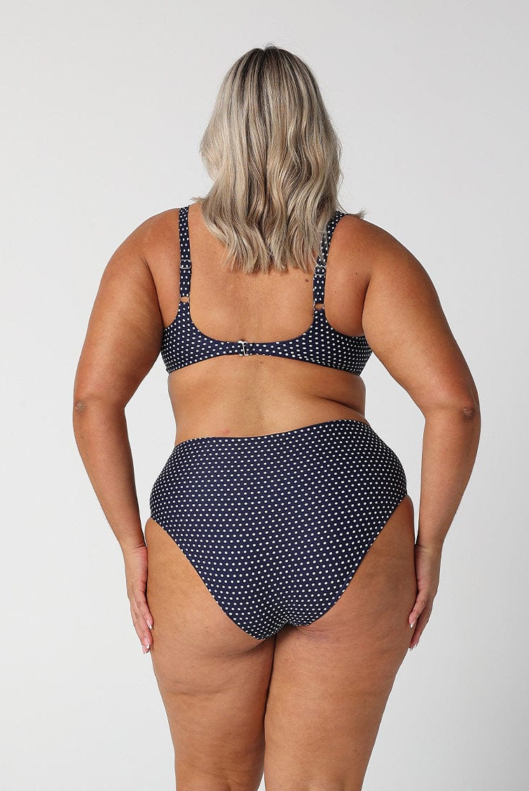 model showing cheeky cut navy polka dot swim bottoms