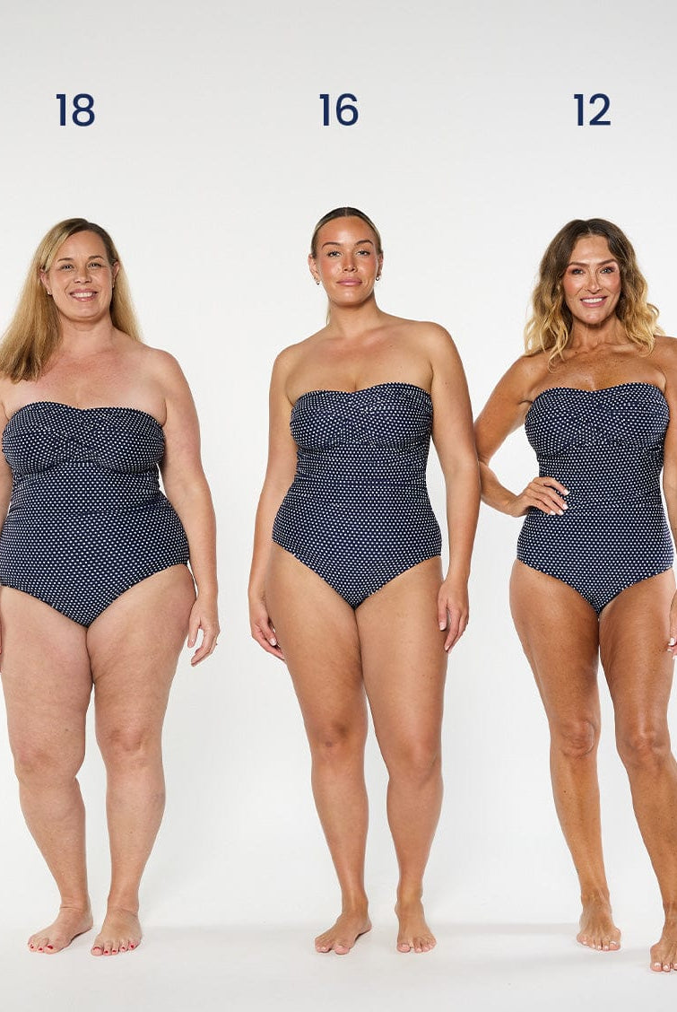 three models wearing navy and white dots bandeau one piece