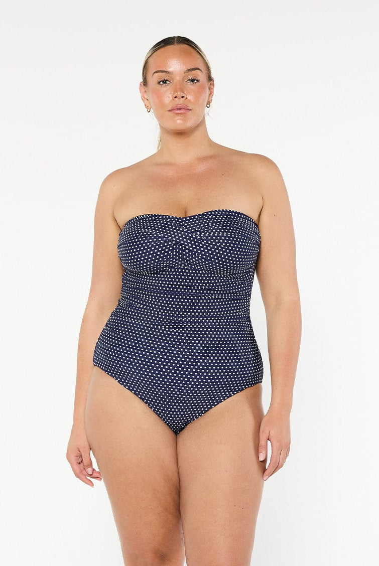 model wearing navy polka dot women's strapless one piece