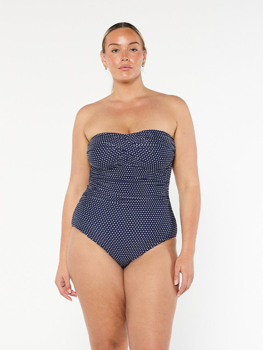 model wearing navy polka dot women's strapless one piece