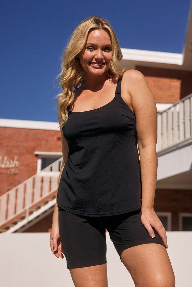 model standing in front of a pool wearing a black above knee boardshort with tie front detail