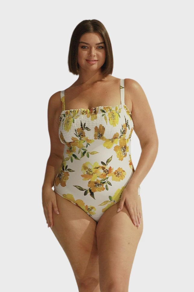 Brunette model wearing curve shirred bandeau one piece in yellow floral with removable straps