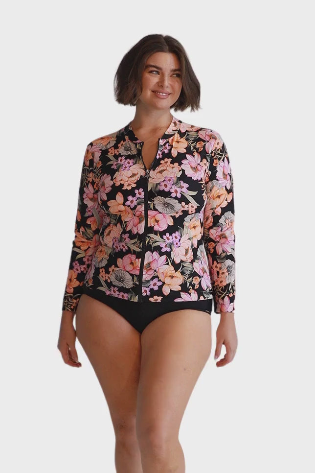 Brunette model wears black and pink floral zip front long sleeve rash vest