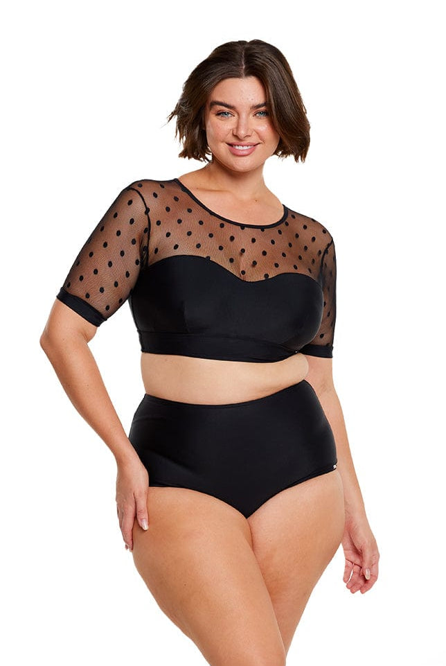 Brunette model wears black polkadot bikini top with mesh short sleeves