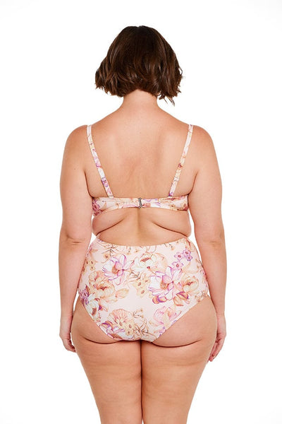 Brunette model wears supportive underwire bandeau bikini top in peach floral print