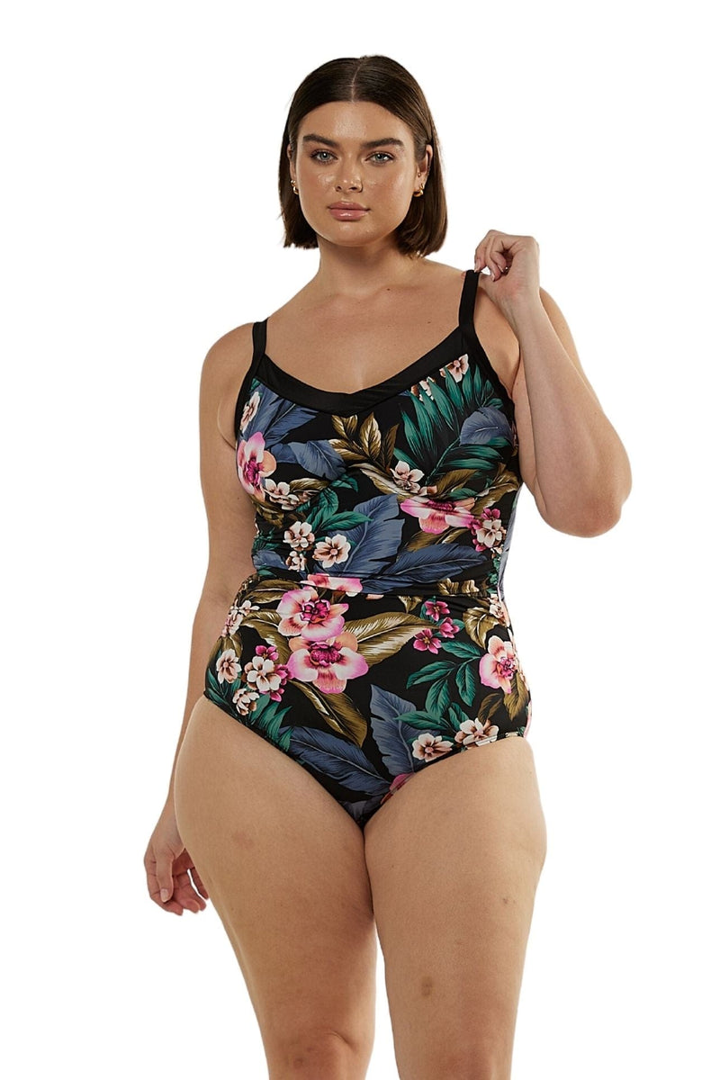 Front profile of brunette curve model wearing underwire one piece swimsuit with floral print