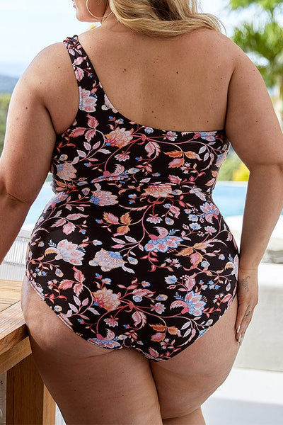 plus size women wears one shoulder one piece in pink and black floral pattern