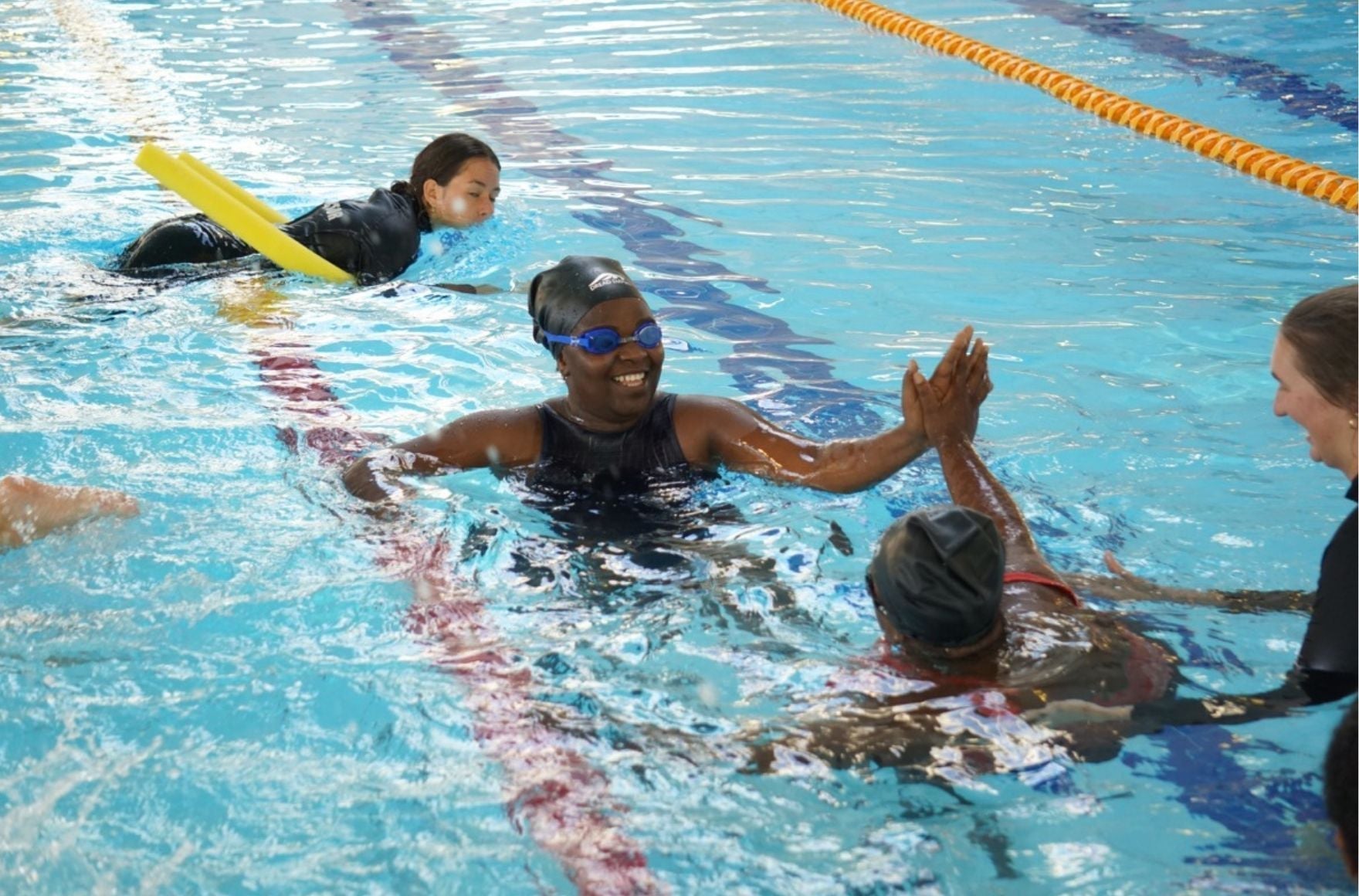 Women high five in the pool during a swimming lesson