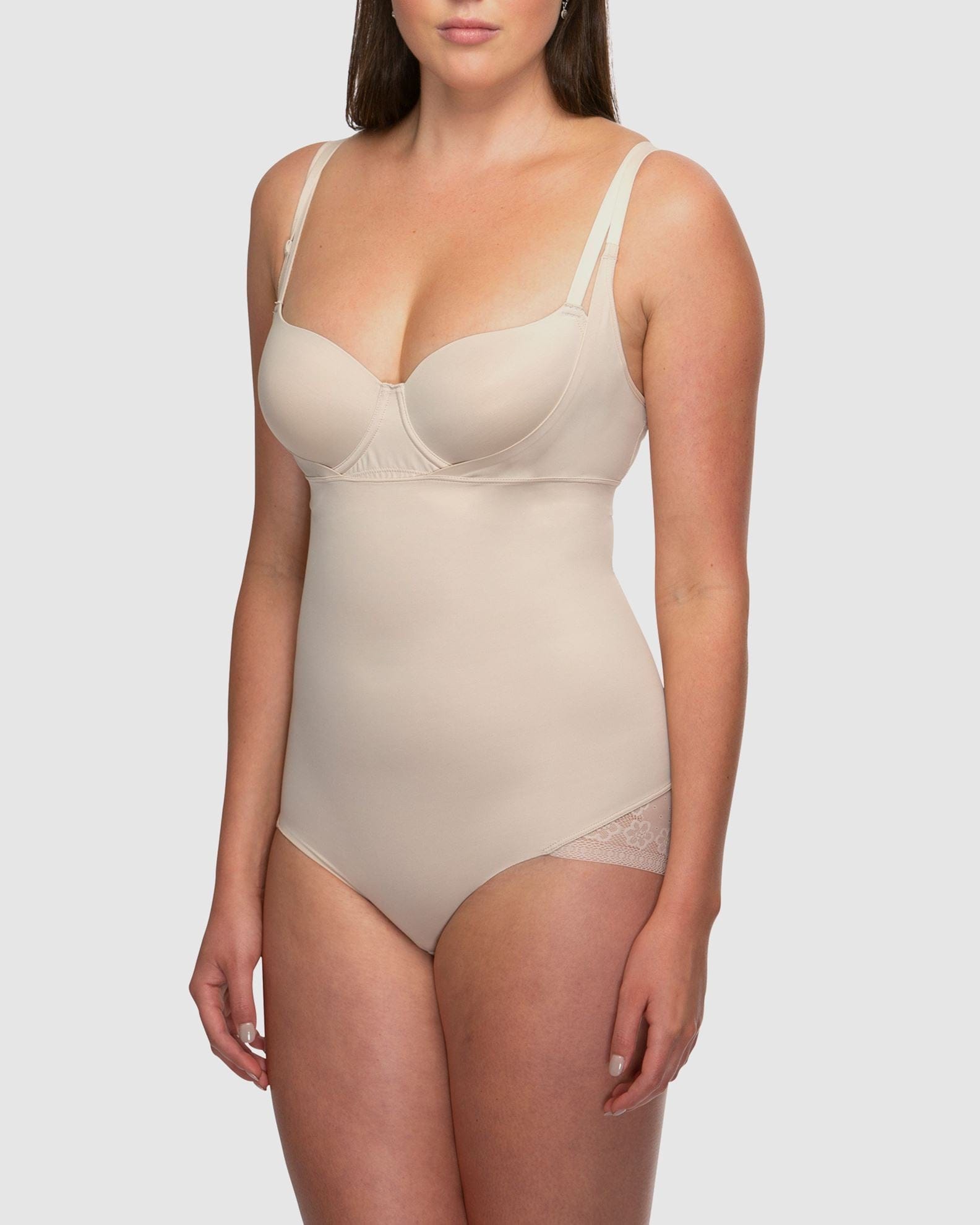 Woman wearing a beige bodysuit against a white background