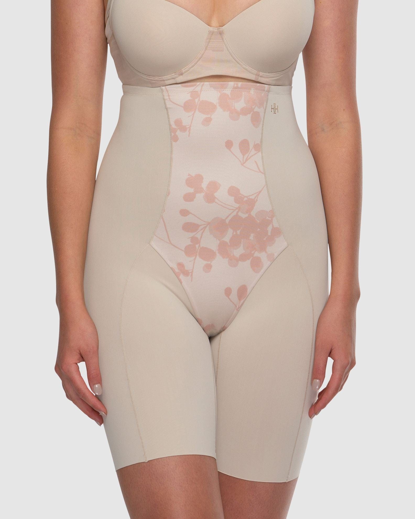 Beige shapewear with floral mesh panel on a plain background