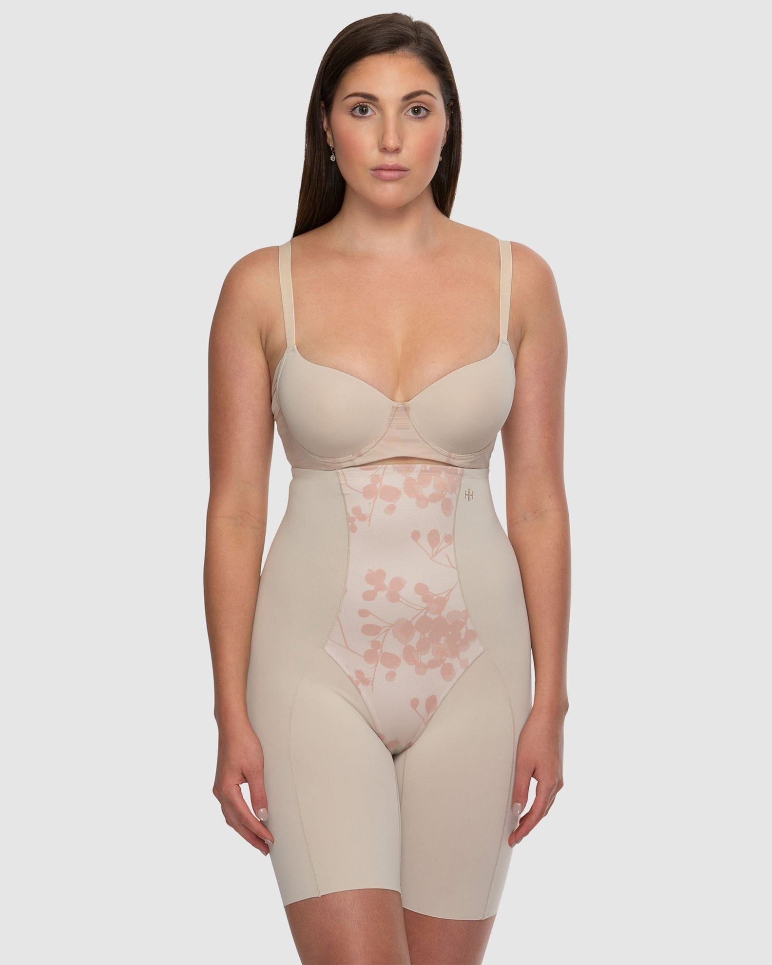 Woman wearing a beige shapewear garment on a white background
