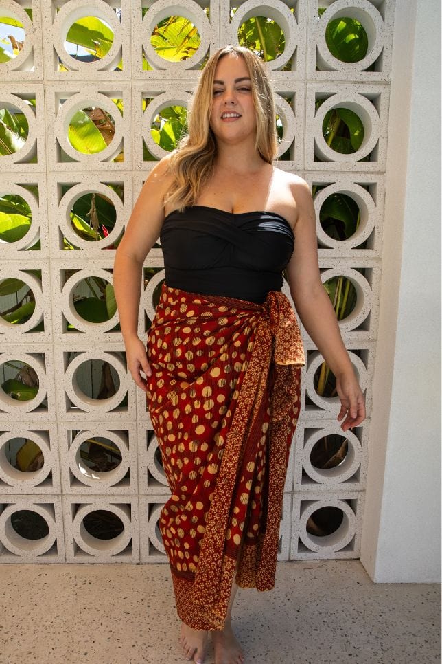 Maroon block printed spot design sarong worn over a black strapless swimsuit