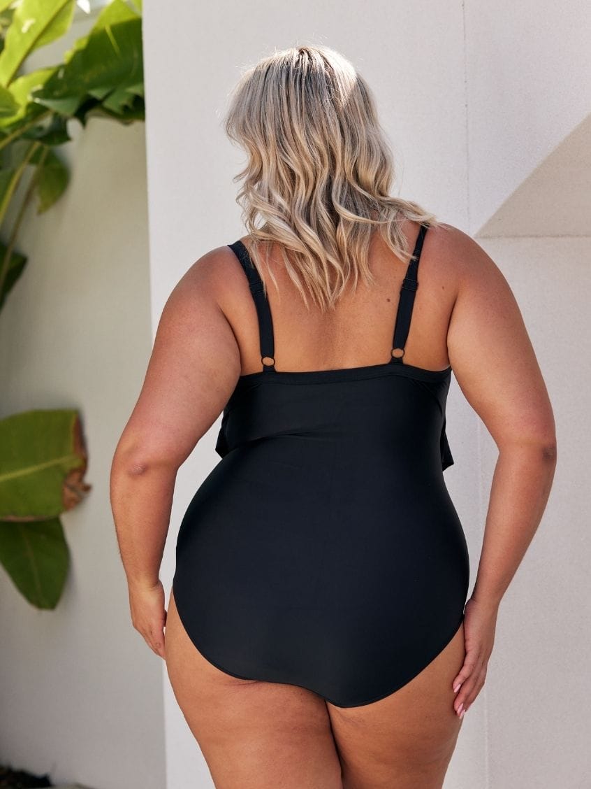 Woman wearing a black ruffled swimsuit by a pool