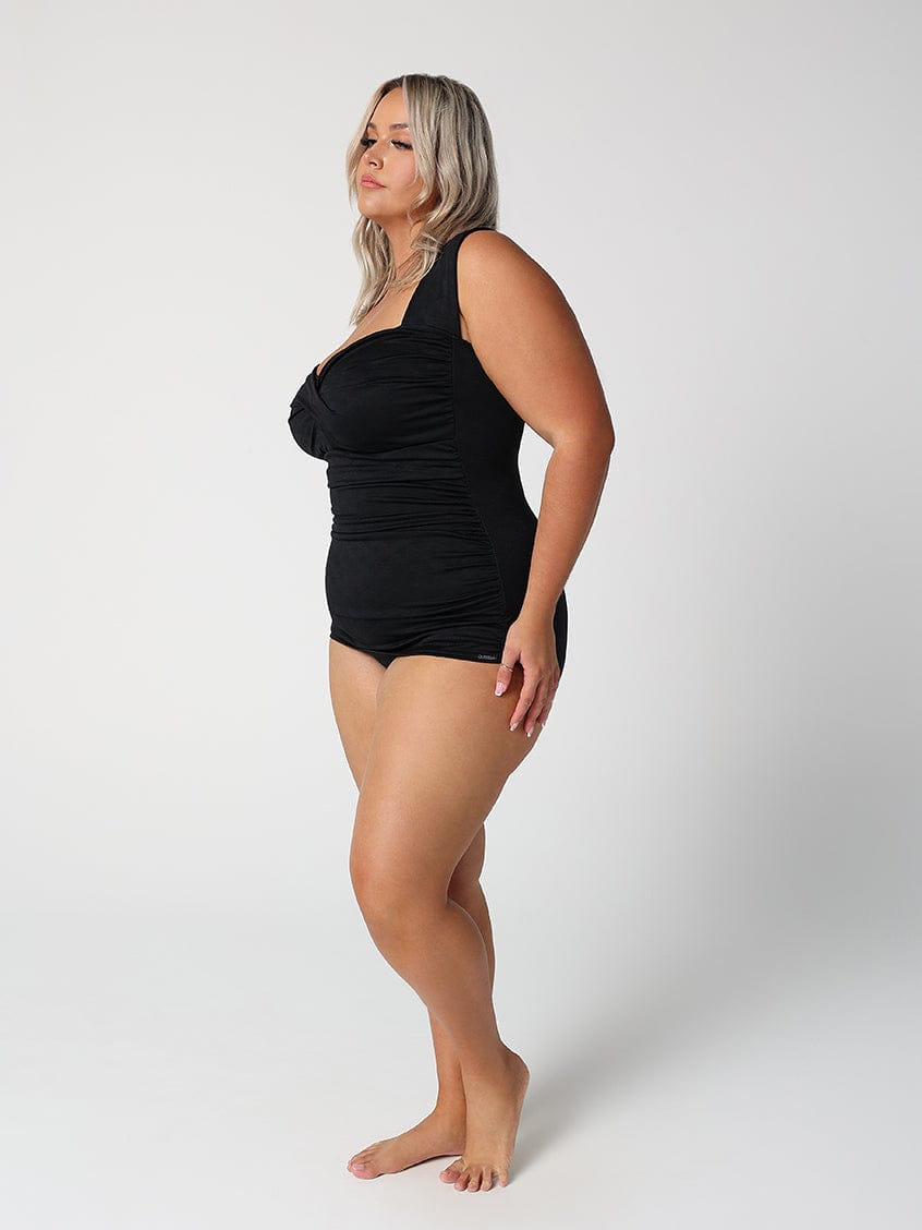 Woman wearing a black swimsuit against a white background