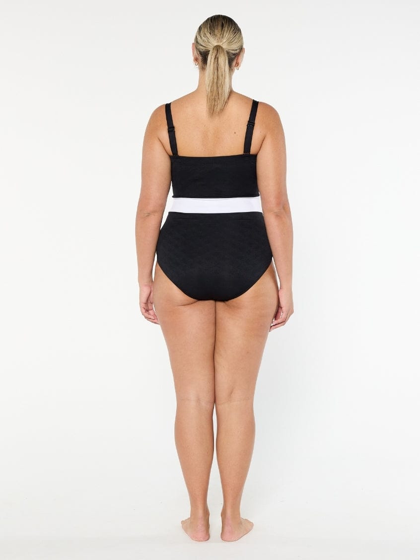 Woman wearing a black swimsuit with white trim on a white background