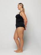 Woman wearing a black tank top and shorts on a white background