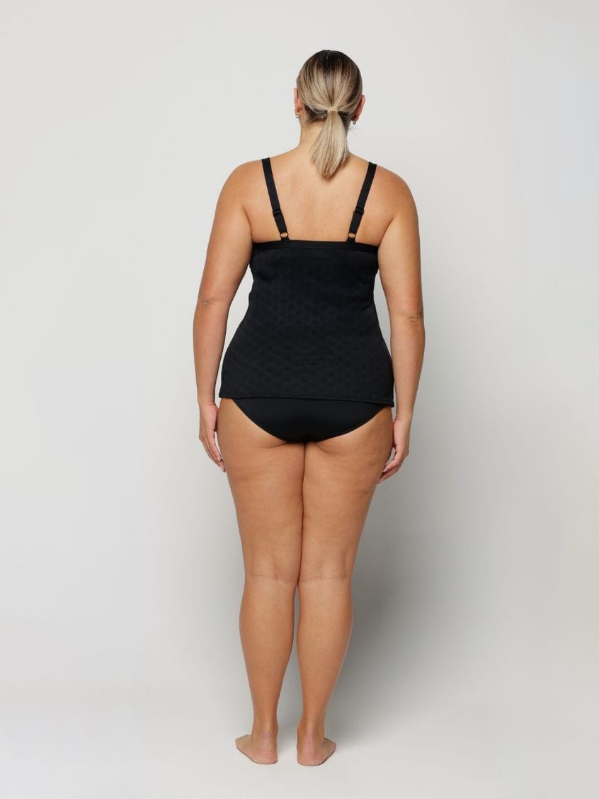 Woman wearing a black swimsuit on a plain background