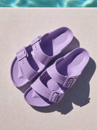 Pair of purple sandals on a diving board with water in the background