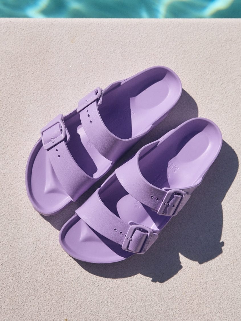 Pair of purple sandals on a diving board with water in the background