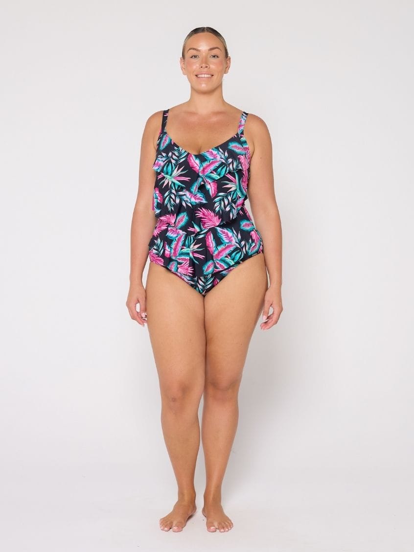 Woman wearing a tropical leaf patterned swimsuit on a white background