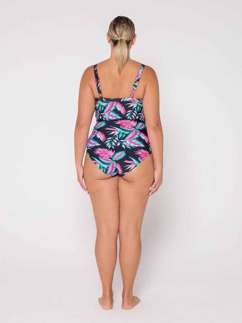 Woman wearing a tropical leaf patterned swimsuit on a white background