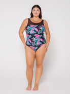 Woman wearing a black swimsuit with pink and green leaf pattern on a white background