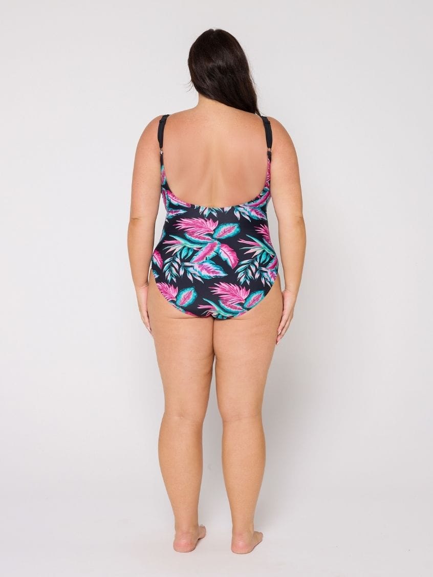 Woman wearing a tropical leaf patterned swimsuit on a white background