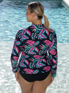 Woman wearing a colorful leaf-patterned swimsuit by a pool