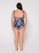 Woman wearing a colorful flamingo patterned tank one piece swimsuit on a white background with scoop back