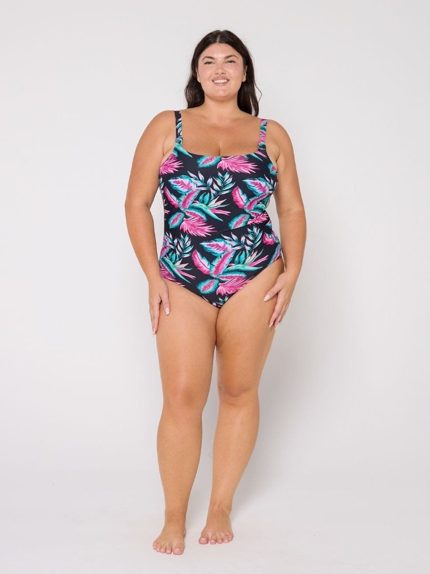 Woman wearing a tropical leaf patterned swimsuit on a white background