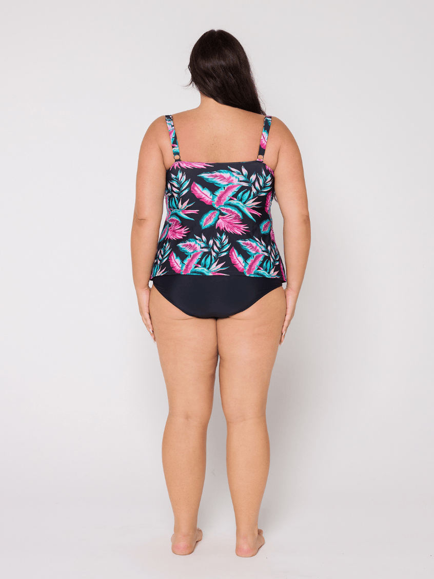 Woman wearing a swimsuit with a tropical leaf pattern on a plain background