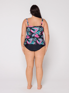 Woman wearing a swimsuit with a tropical leaf pattern on a plain background