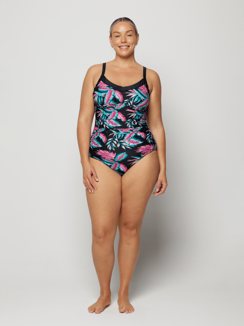 Woman wearing a tropical leaf patterned swimsuit on a plain background