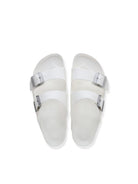A pair of white double-strap slide sandals with silver buckle closures, photographed from a top-down perspective on a clean white background.