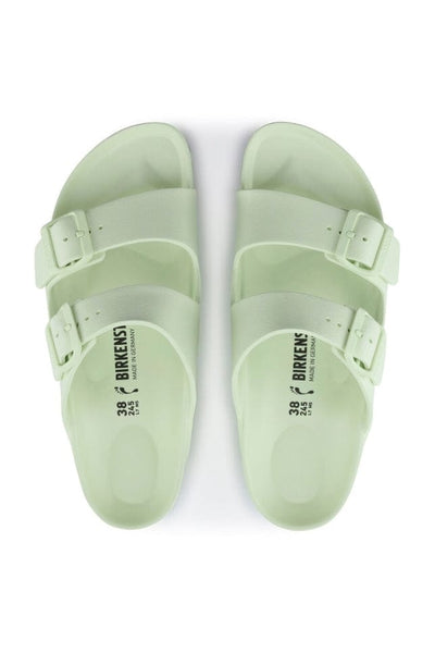 top angle photo of faded lime green slides with side buckles in a light rubber