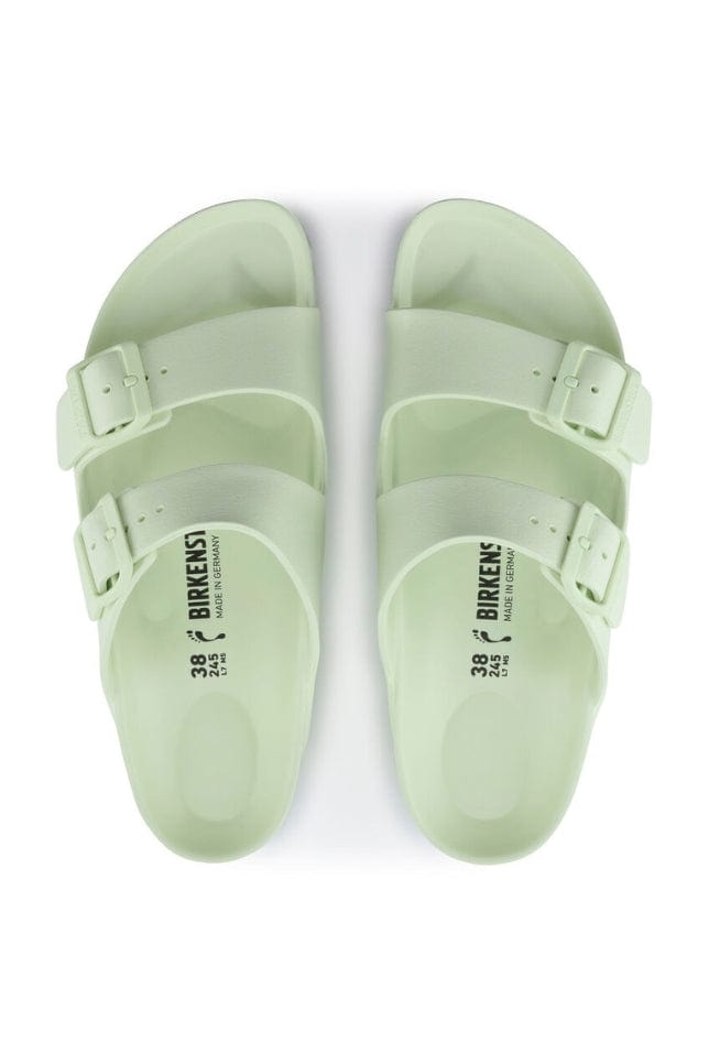 top angle photo of faded lime green slides with side buckles in a light rubber