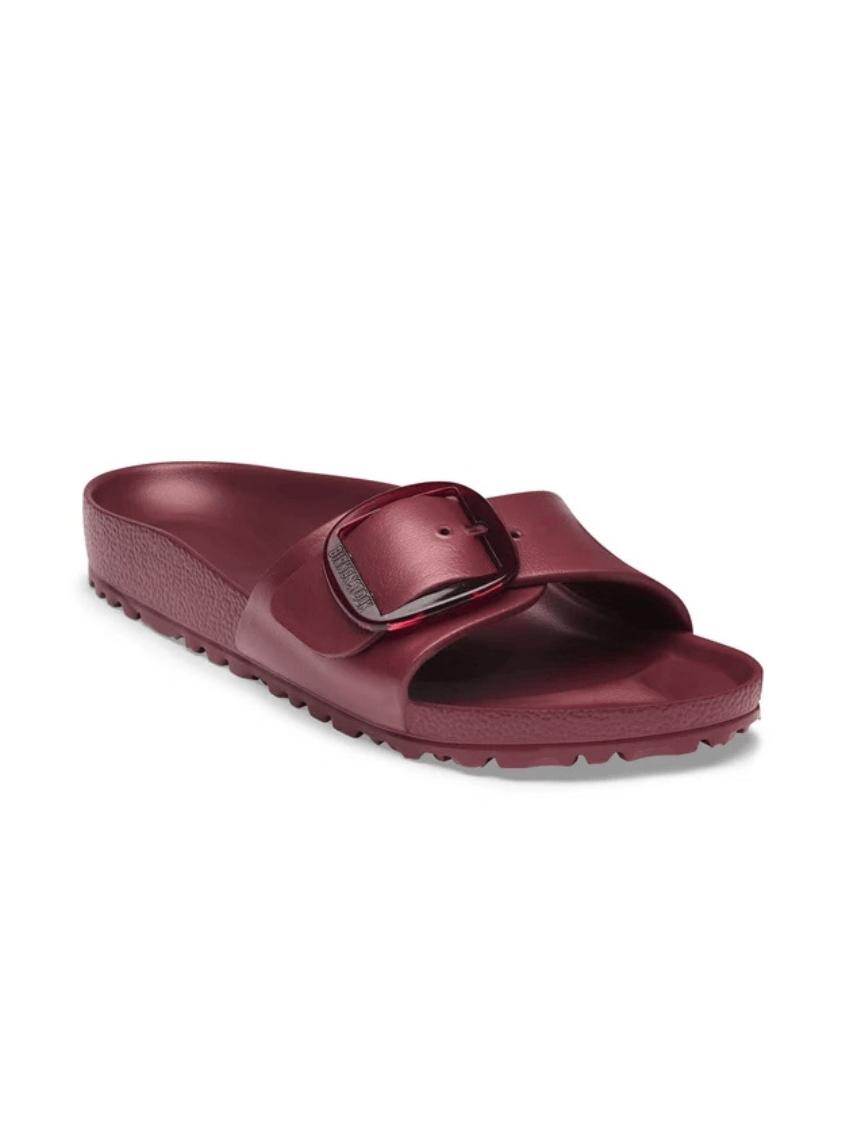 A single burgundy slide sandal with a wide strap and a metallic buckle detail, shown from a three-quarters angle on a white background.