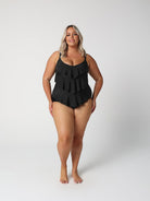 Woman wearing a black ruffled swimsuit on a white background