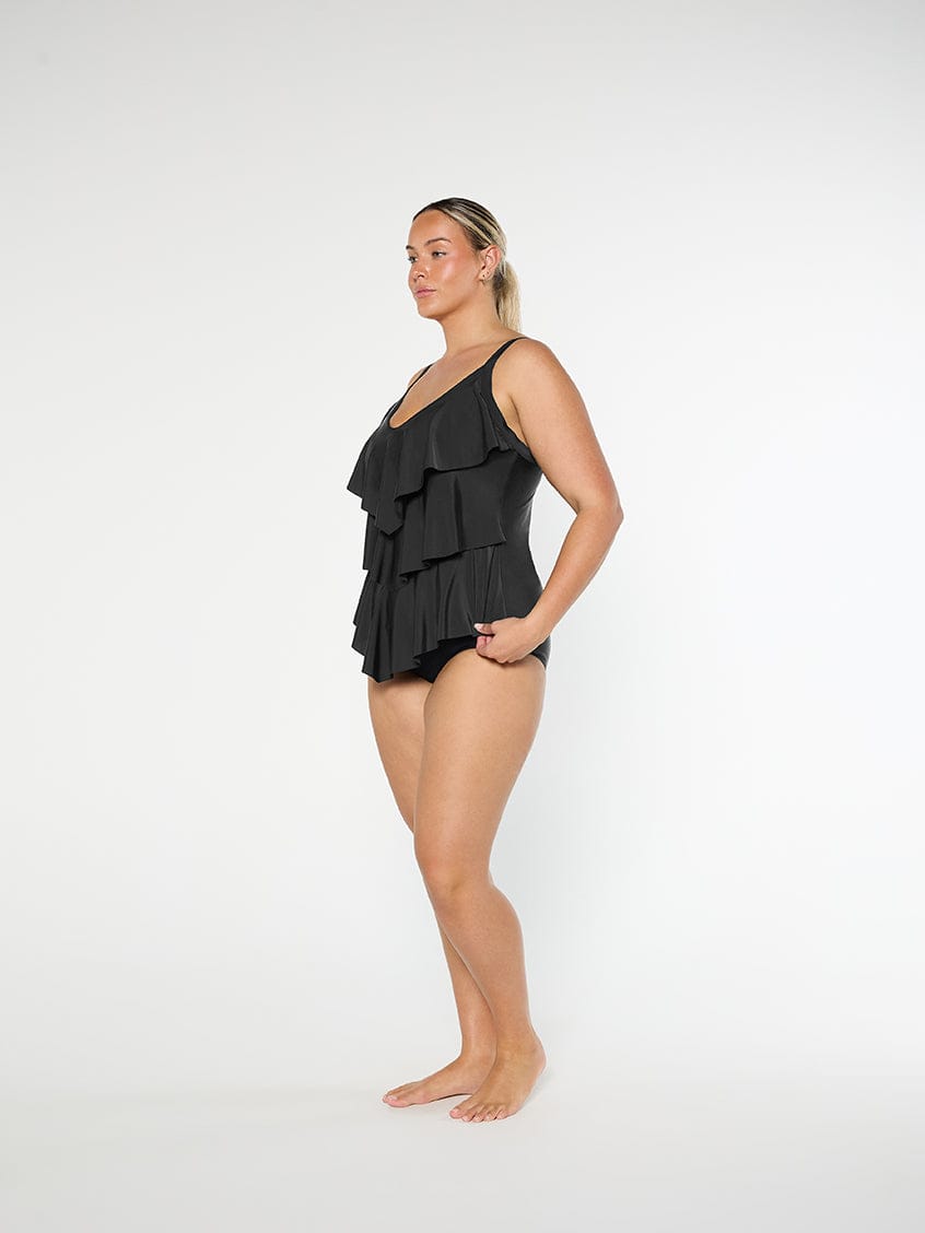 Woman wearing a black ruffled swimsuit on a white background