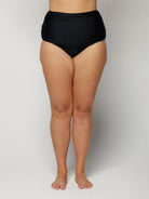Person wearing black high-waisted bikini bottoms on a plain background