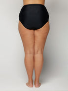 Person wearing black high-waisted underwear on a plain background