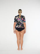 Woman wearing a floral shirt and black swimsuit on a white background